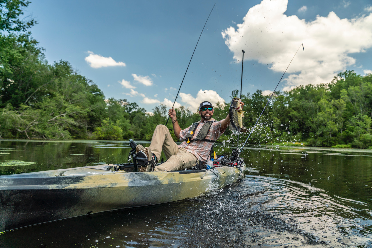 Kayak da pesca in un lago, con un pescatore cha ha appena preso un grosso pesce, nel suo tempo libero